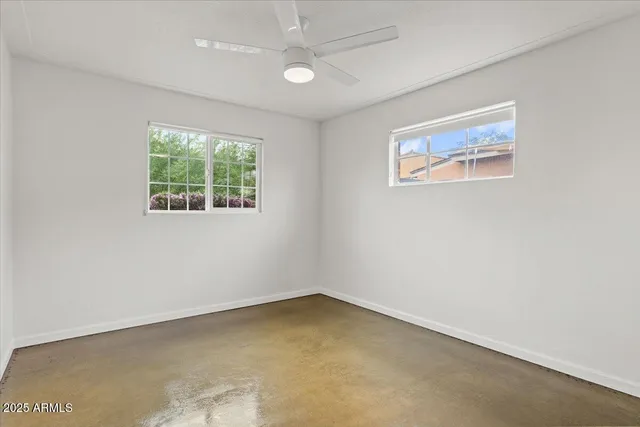 an empty room with windows and fan
