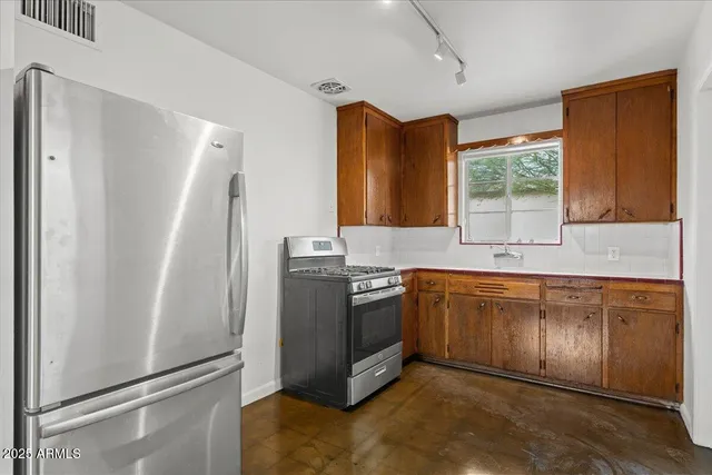 a kitchen with stainless steel appliances granite countertop a refrigerator a sink a stove a washer dryer and a refrigerator