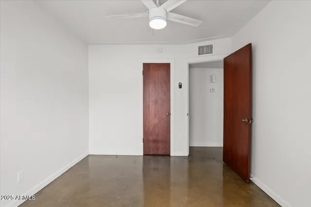 an empty room with closet and a chandelier fan