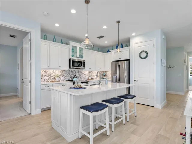 a kitchen with stainless steel appliances kitchen island granite countertop a sink and refrigerator