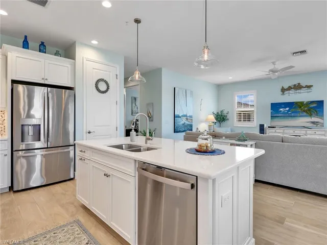 a kitchen with stainless steel appliances granite countertop a sink a stove a refrigerator and island with wooden floor