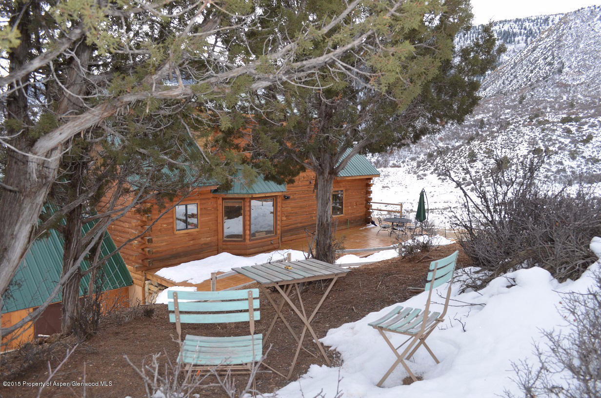 142 Happy Dog Trail Rifle, CO 81650 - Photo 28 of 39 a view of a patio with table and chairs with wooden fence and large trees
