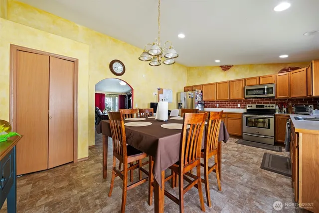 a kitchen with stainless steel appliances granite countertop a table chairs and a refrigerator
