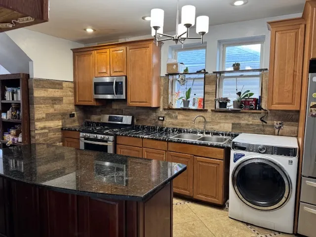 a kitchen with kitchen island granite countertop a sink appliances and cabinets