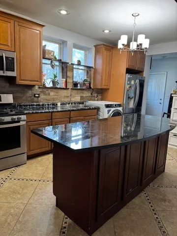 a kitchen with kitchen island granite countertop a stove top oven a sink dishwasher a dining table and chairs with wooden floor