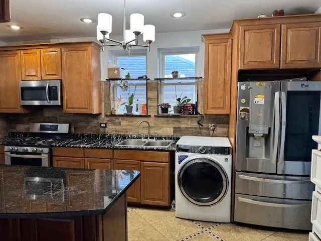 a kitchen with stainless steel appliances granite countertop a sink a stove and a wooden cabinets