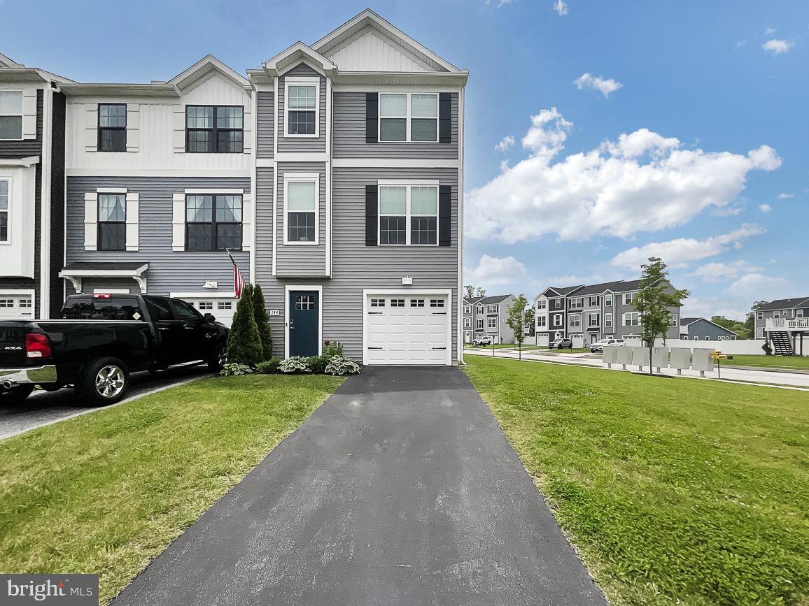 a view of a house with a yard and cars parked