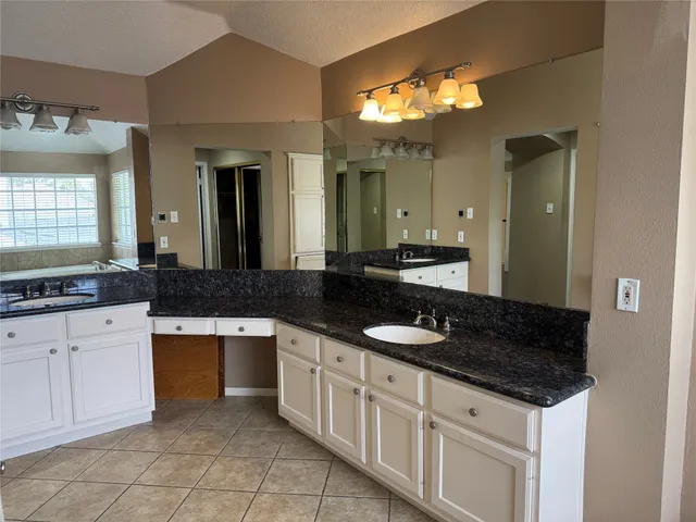 a spacious bathroom with a granite countertop sink a mirror and a vanity