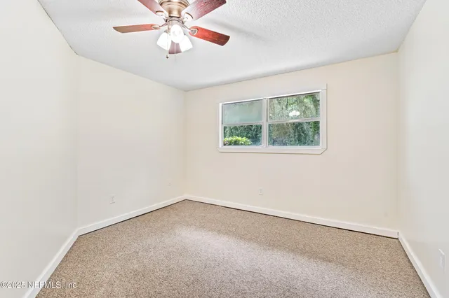 an empty room with a window and a fan