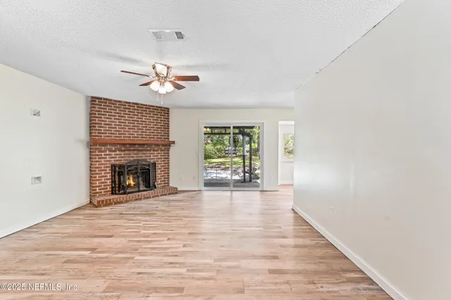 a view of an empty room with a fireplace and a window