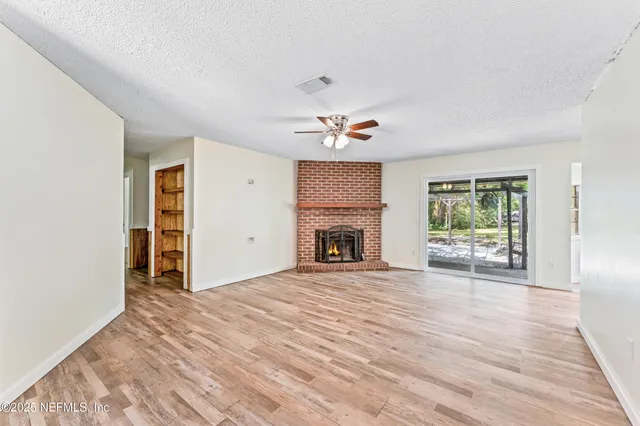 a view of an empty room with a fireplace and a window