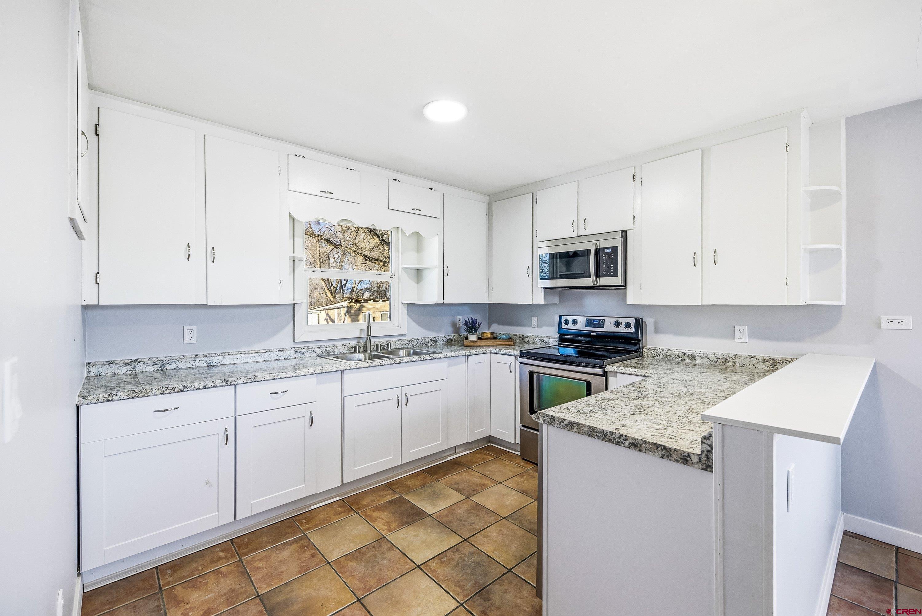 6038 Townsend Road Delta, CO 81416 - Photo 41 of 45 a kitchen with granite countertop white cabinets sink and stainless steel appliances