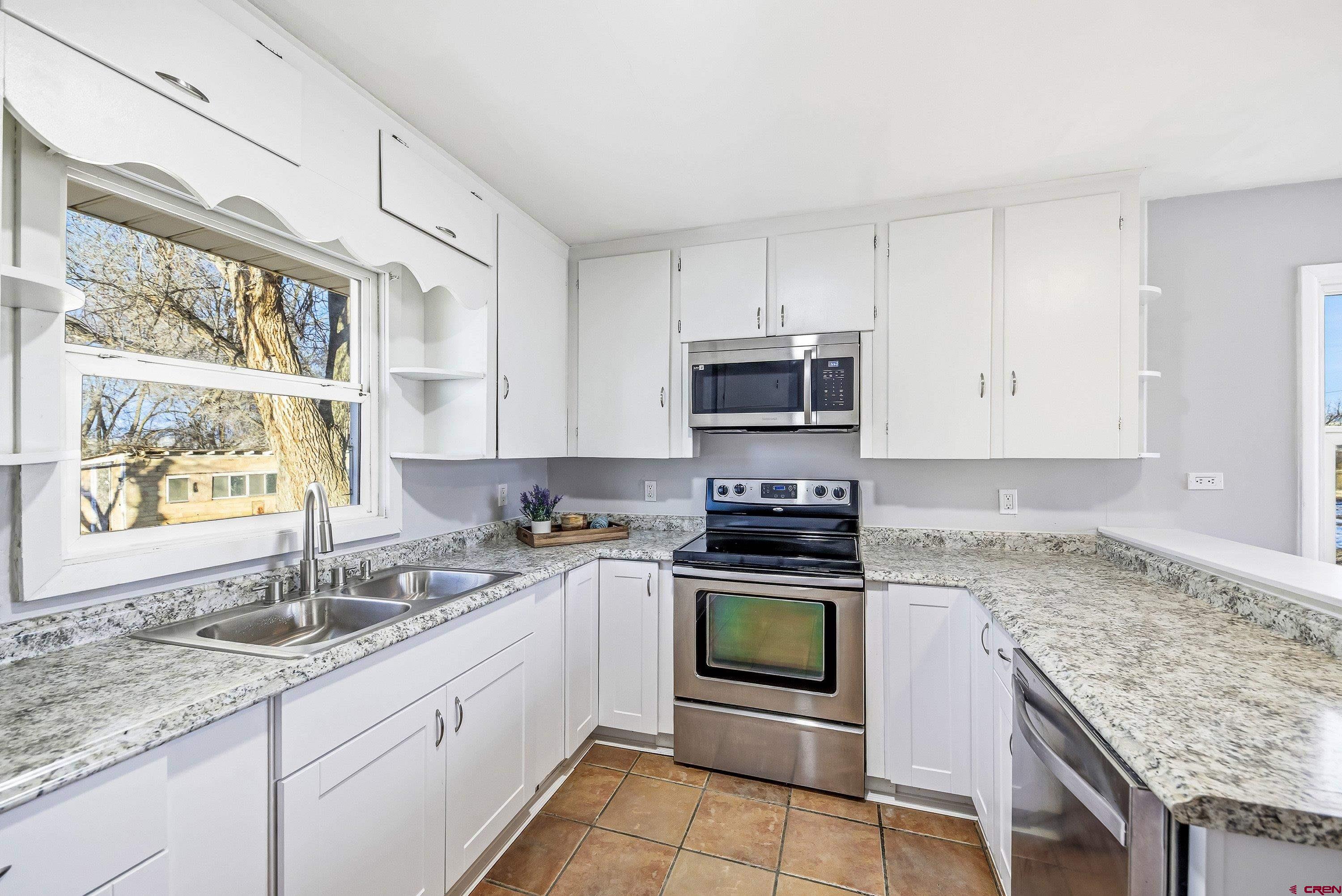 6038 Townsend Road Delta, CO 81416 - Photo 43 of 45 a kitchen with granite countertop a sink stainless steel appliances and white cabinets