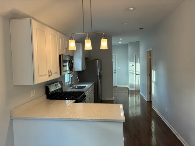 a kitchen with kitchen island granite countertop a sink a stove and a refrigerator