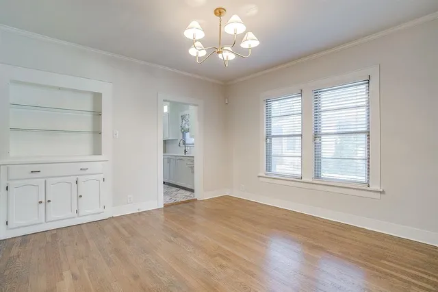 an empty room with wooden floor cabinet and windows