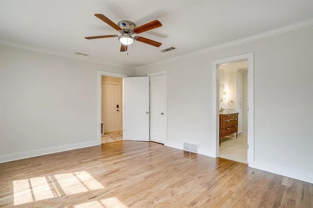 a view of empty room with wooden floor and ceiling fan