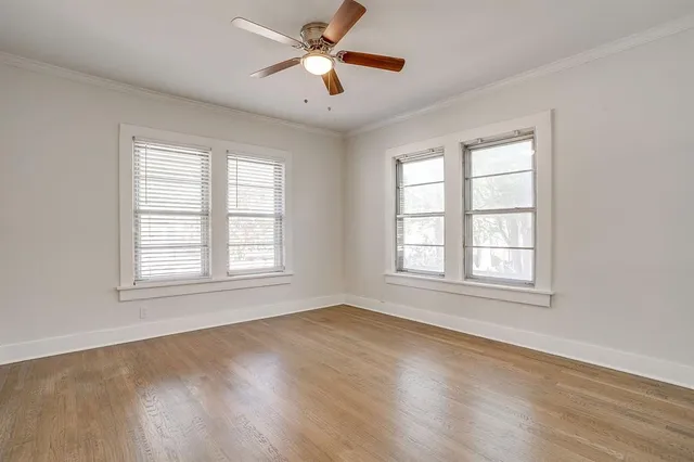 a view of an empty room with chandelier fan and wooden floor