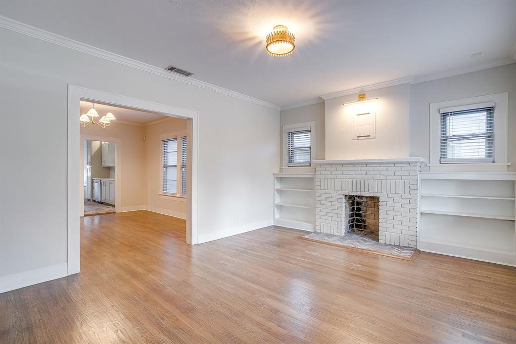 2209 West Rosedale Street South Fort Worth, TX 76110 - Photo 7 of 40 an empty room with wooden floor fireplace and windows