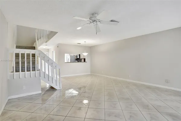 an empty room with windows and ceiling fan