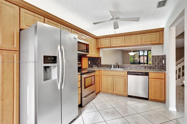a kitchen with stainless steel appliances granite countertop a refrigerator and a stove top oven