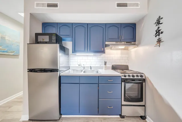 a kitchen with stainless steel appliances a refrigerator a sink and wooden cabinets