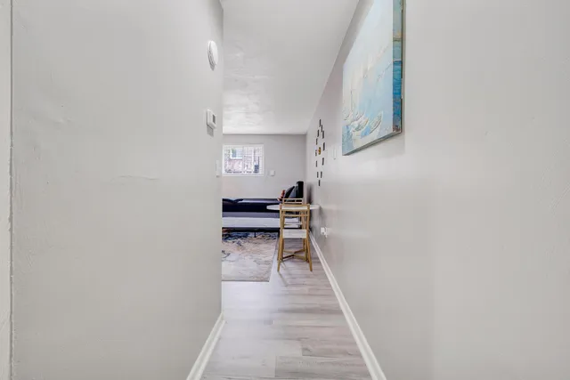 a hallway with wooden floor and a bathroom