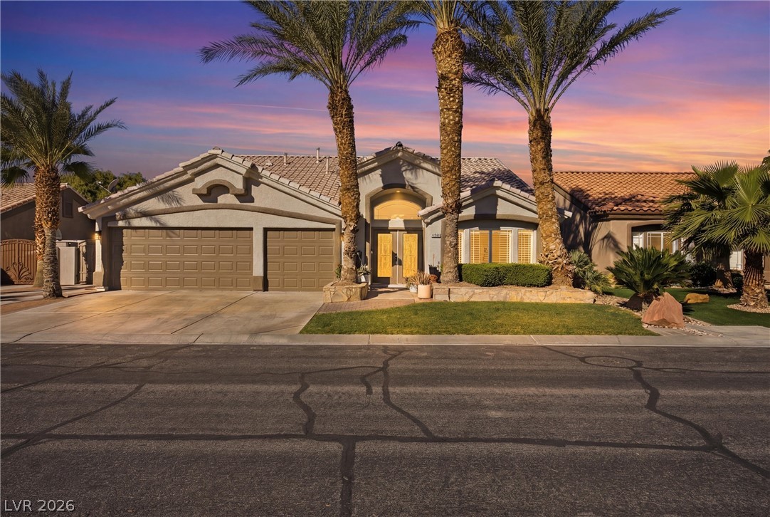 Mediterranean / spanish-style house with a tile roof, an attached garage, stucco siding, and driveway