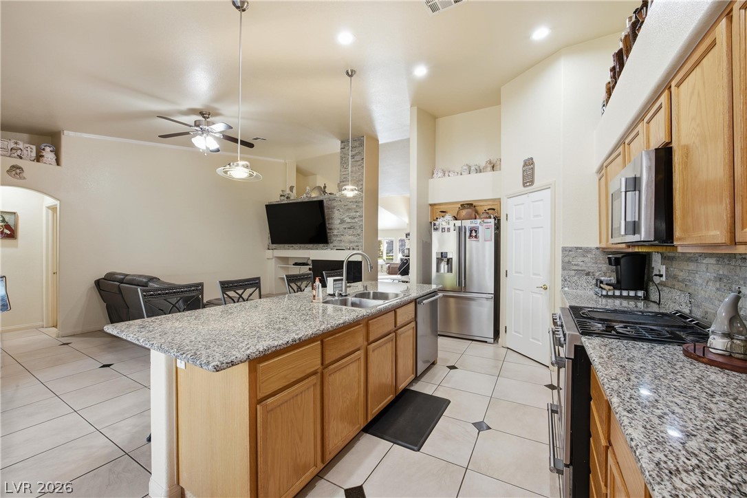 6109 Ocho Rios Street Las Vegas, NV 89130 - Photo 35 of 36 Kitchen featuring open floor plan, stainless steel appliances, ceiling fan, light tile patterned flooring, and a kitchen island with sink