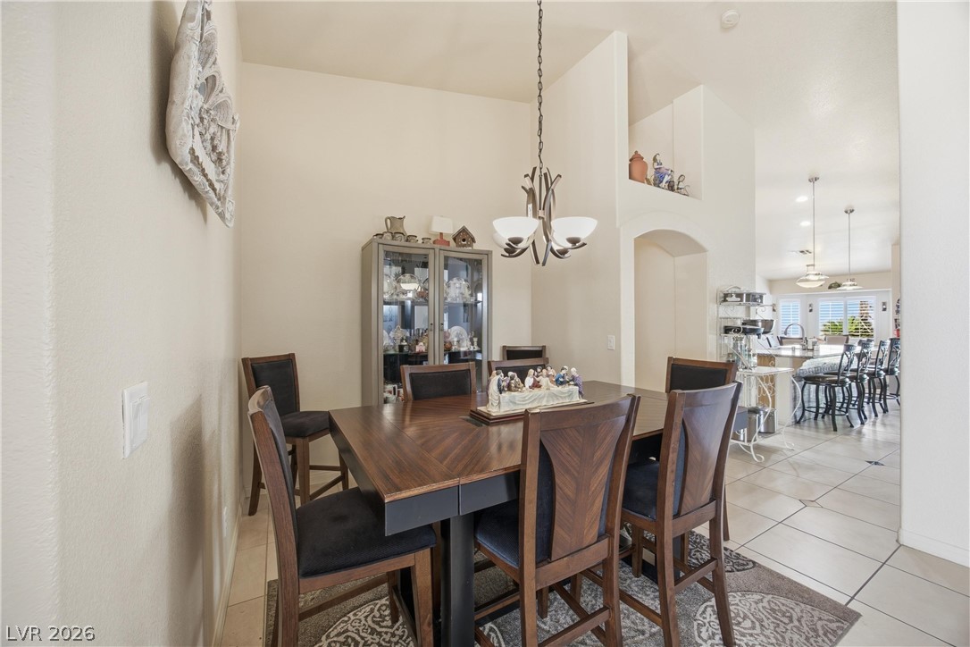 6109 Ocho Rios Street Las Vegas, NV 89130 - Photo 18 of 36 Dining space featuring light tile patterned floors, arched walkways, lofted ceiling, and hanging lights