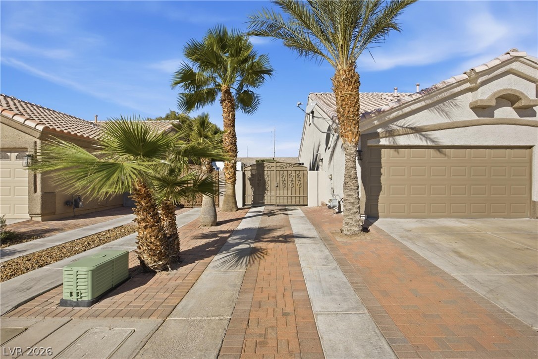 6109 Ocho Rios Street Las Vegas, NV 89130 - Photo 4 of 36 View of home's exterior featuring a gate, stucco siding, driveway, and a garage