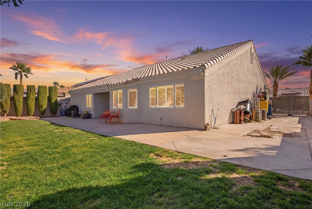 6109 Ocho Rios Street Las Vegas, NV 89130 - Photo 6 of 36 Back of property at dusk featuring stucco siding, a patio, a gate, and a tile roof