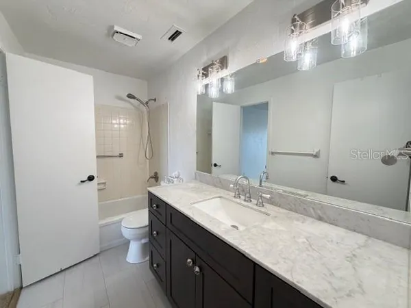 a bathroom with a granite countertop sink a toilet and shower