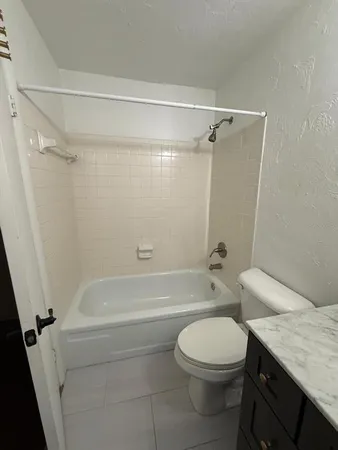 a bathroom with a granite countertop bathtub shower sink vanity and toilet