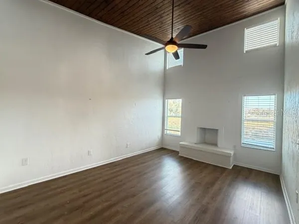 an empty room with wooden floor fan and windows
