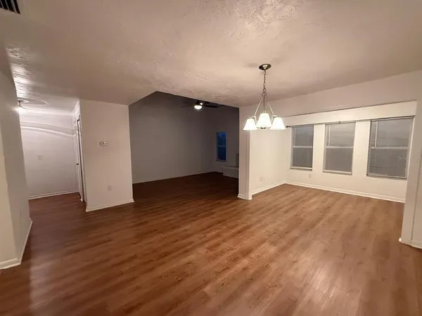 a view of an empty room with wooden floor and windows