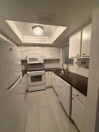 a kitchen with granite countertop a stove a sink and a refrigerator