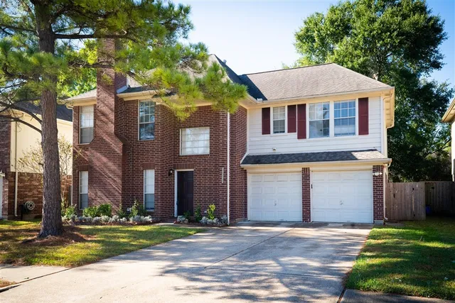 a front view of a house with a garden and trees