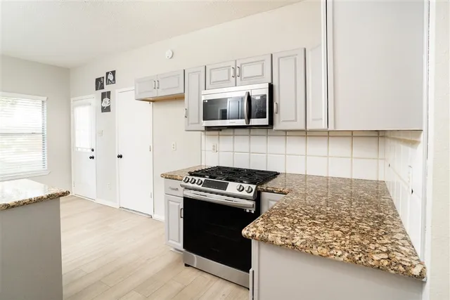 a kitchen with granite countertop a stove and a microwave