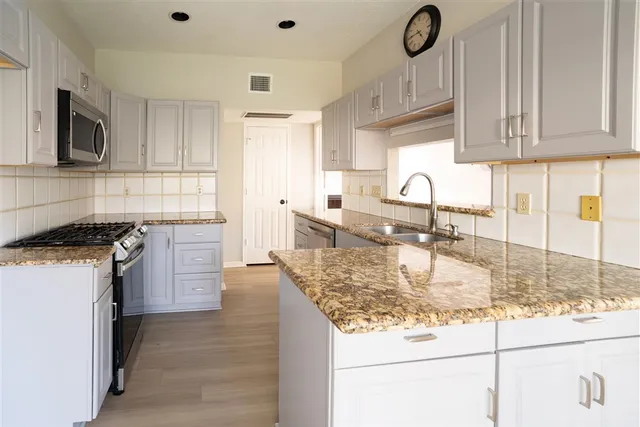 a kitchen with stainless steel appliances granite countertop a sink stove and cabinets