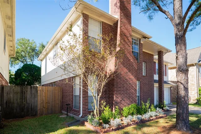a view of a brick house with a yard and large tree