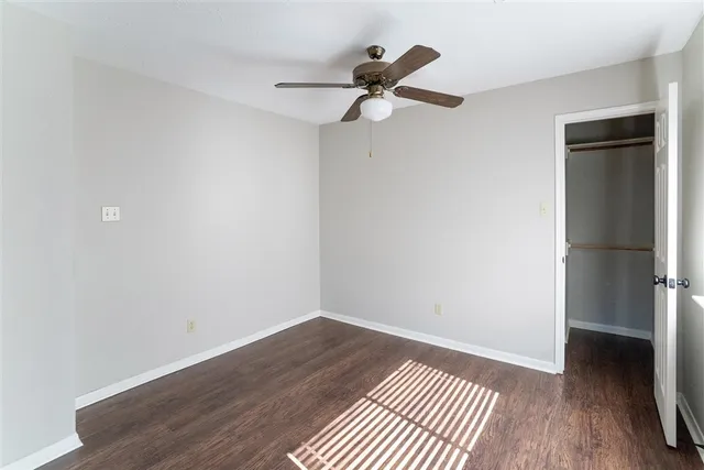 an empty room with wooden floor fan and windows