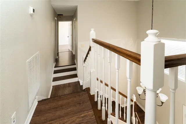 an empty room with wooden floor ceiling fan and windows