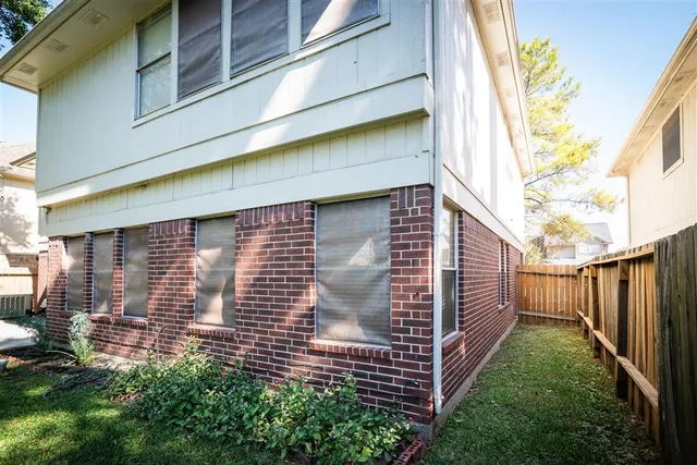 a view of a backyard with large trees and wooden fence