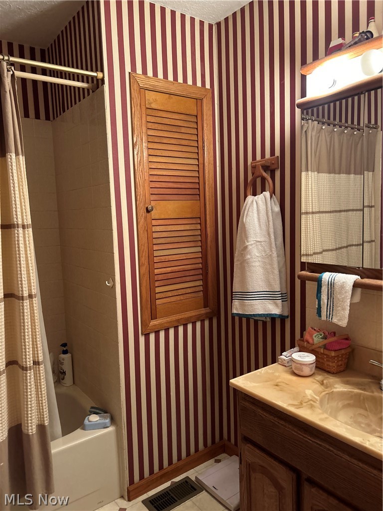 73323 Old Twenty One Road Kimbolton, OH 43749 - Photo 10 of 14 Full bath featuring wallpapered walls, a textured ceiling, vanity, shower / tub combo with curtain, and light tile patterned flooring