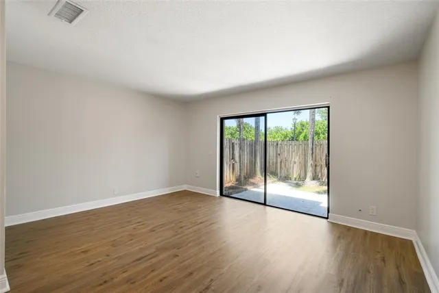 an empty room with wooden floor and windows