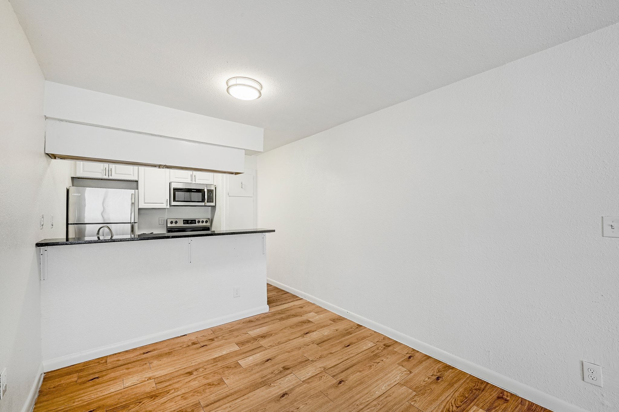 2207 Leon Street, Unit 201 Austin, TX 78705 - Photo 5 of 19 Kitchen featuring stainless steel appliances, a peninsula, white cabinetry, and light wood-style floors