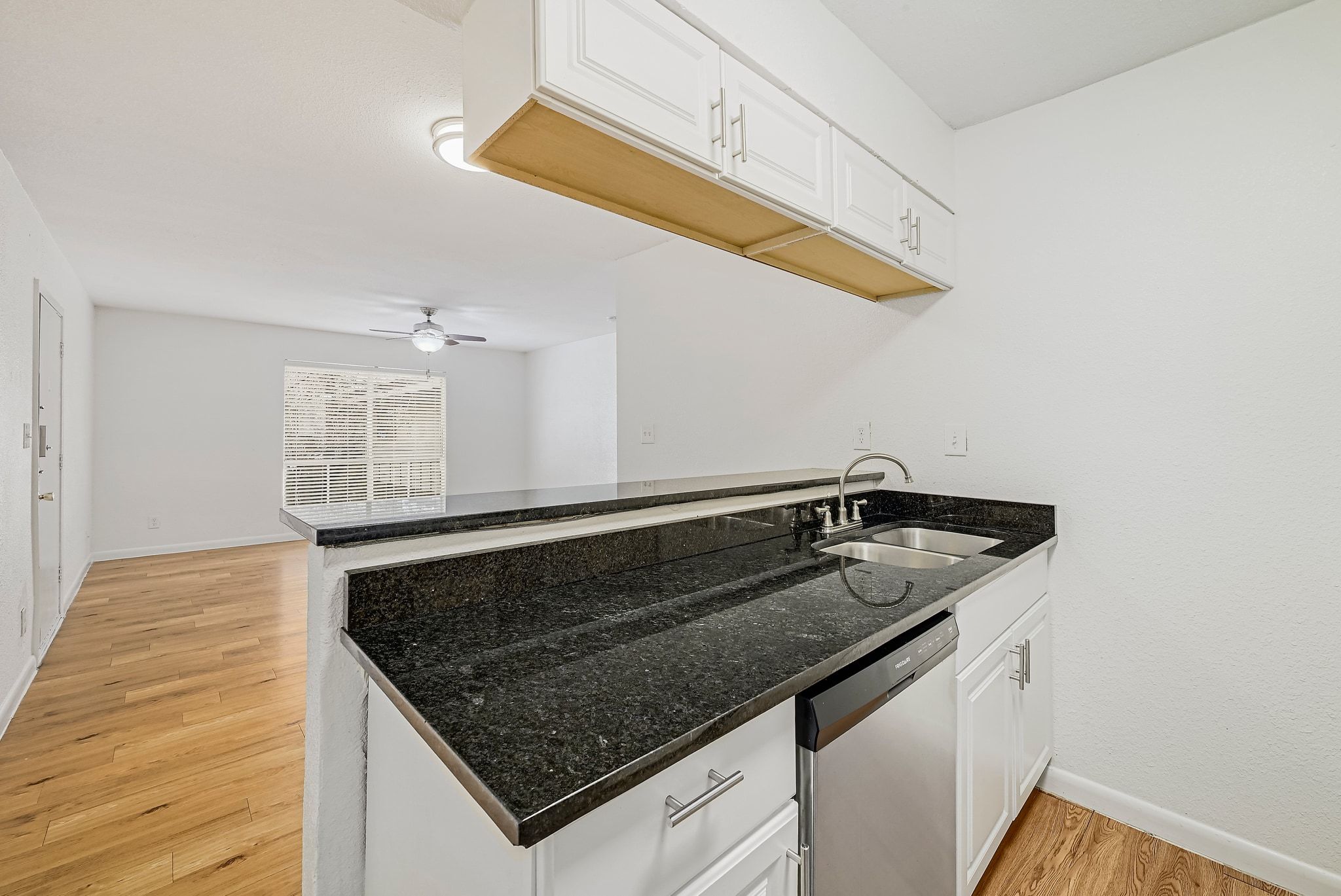 2207 Leon Street, Unit 201 Austin, TX 78705 - Photo 6 of 19 Kitchen with white cabinetry, dishwasher, dark stone countertops, light wood-style floors, and a peninsula