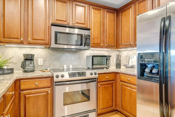 a kitchen with stainless steel appliances granite countertop a stove a sink and a microwave