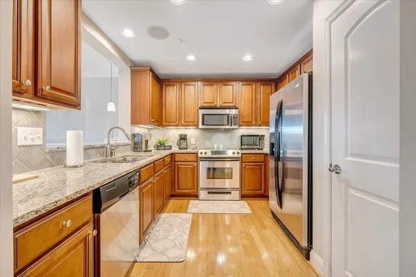 a large kitchen with granite countertop a large counter top stainless steel appliances and cabinets