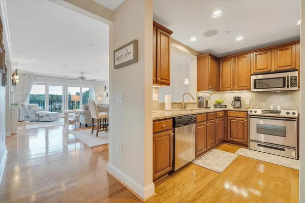 a kitchen with stainless steel appliances granite countertop a stove top oven a sink dishwasher a dining table and chairs with wooden floor